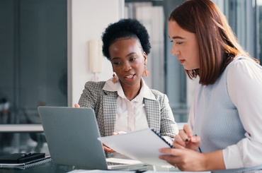 Paper, laptop and people in office for meeting, financial planning and business discussion. Women, document or tech at table for admin, budget review or audit information for company growth and taxes
