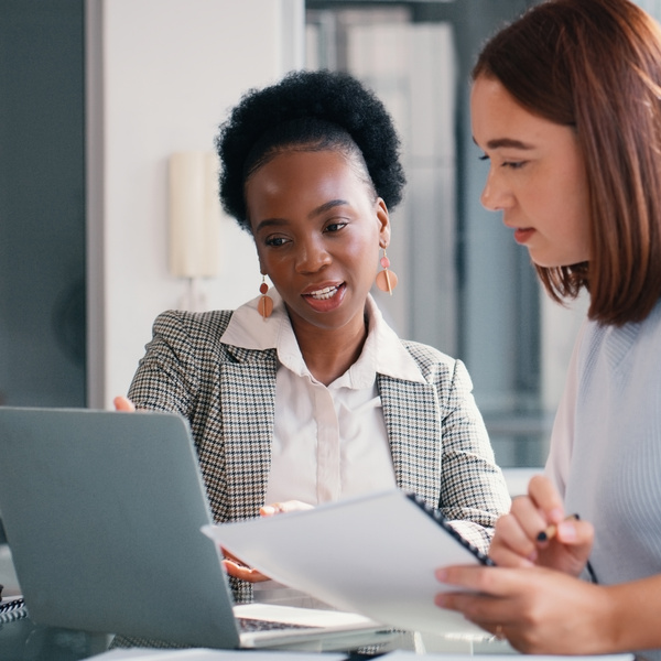 Paper, laptop and people in office for meeting, financial planning and business discussion. Women, document or tech at table for admin, budget review or audit information for company growth and taxes