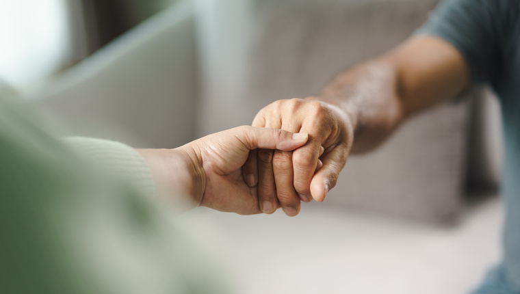 Female friend or family sitting and hold hands during cheer up to mental depress man, Psychologist provides mental aid to patient. PTSD Mental health concept
