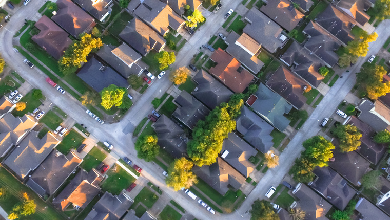 Aerial view of residential houses and driveways neighborhood during a fall sunset. Tightly packed homes, surrounds with green tree flyover in Houston, Texas, US. Suburban housing community development