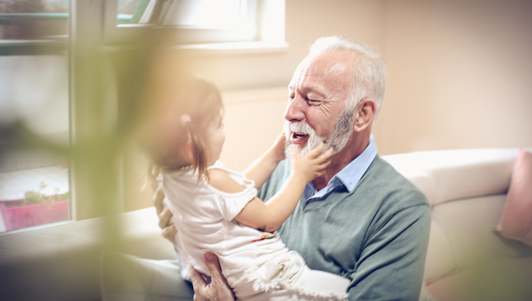 Grandfather at home playing with his granddaughter.