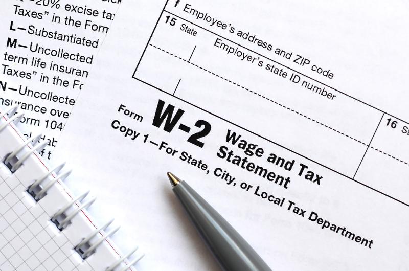 The pen and notebook on the tax form W-2 Wage and Tax Statement. The time to pay taxes